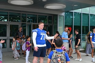 High School student greets elementary students at the door