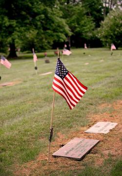 american flag placed next to cemetery head stone 