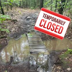 muddy flooded trail with closure sign