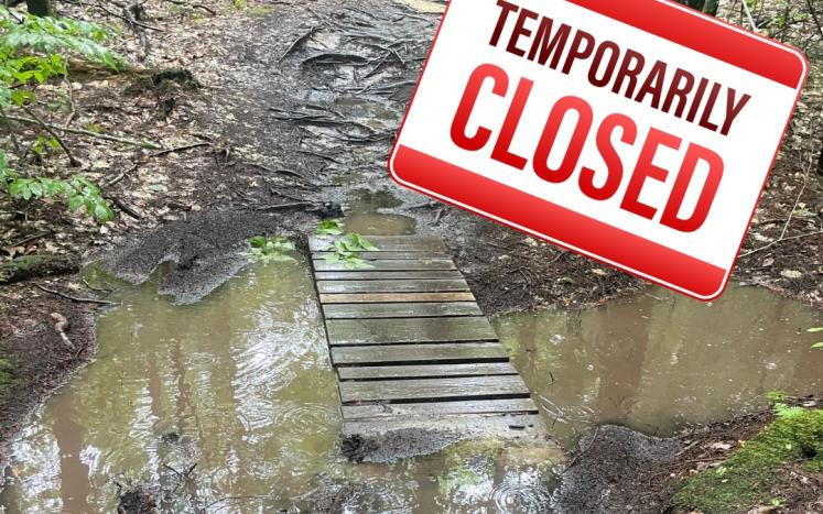 Flooded trail with temporarily closed sign superimposed over it